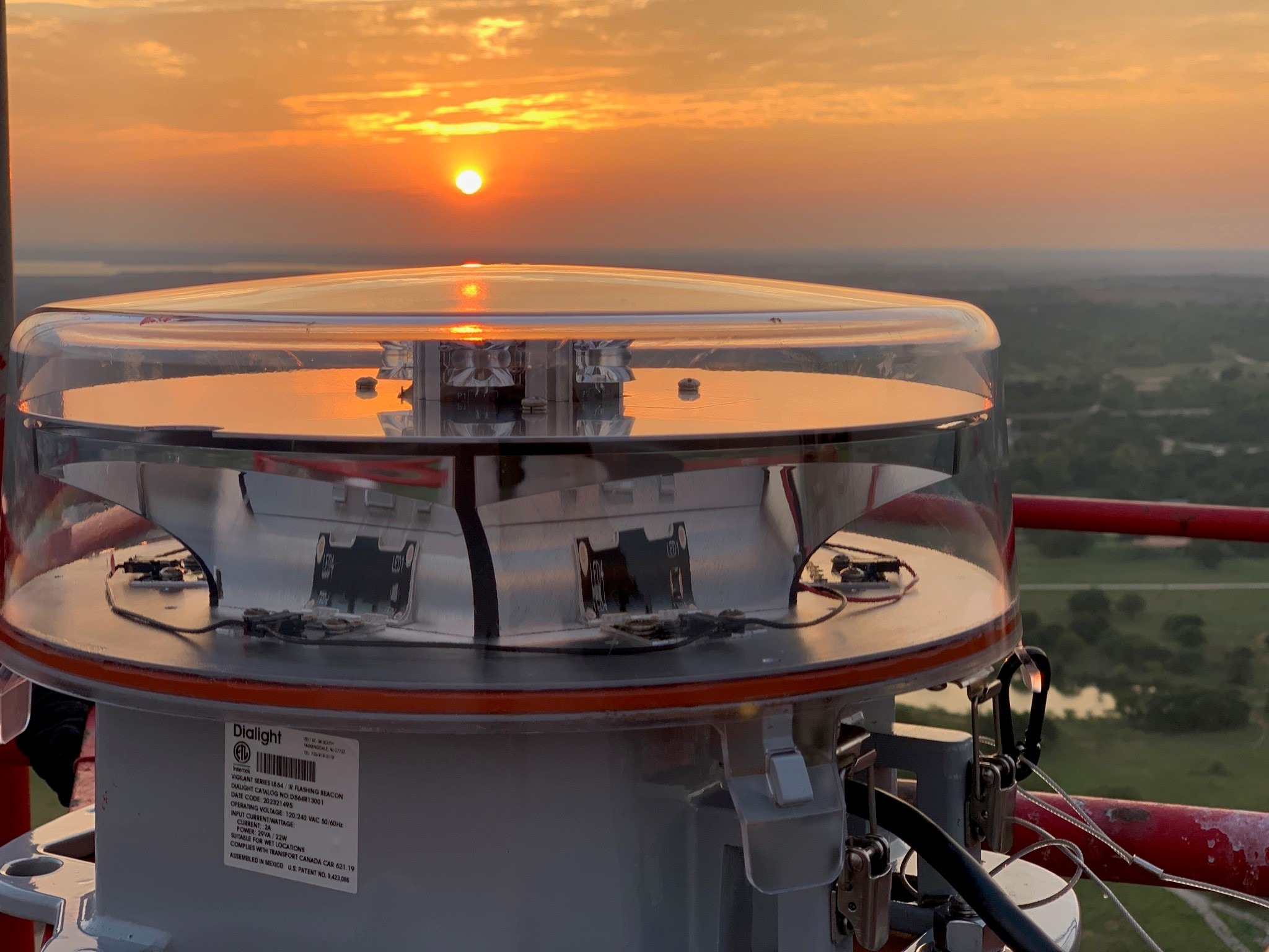 FAA obstruction beacon lit on a tower at sunset