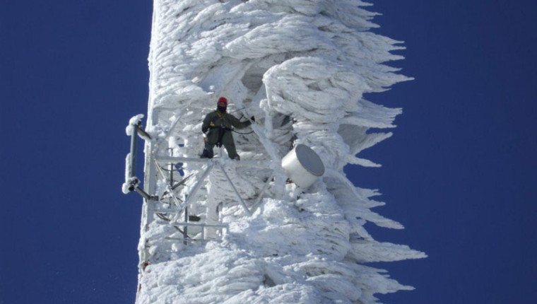 Tower climber working on a communications tower covered in wind-blown ice
